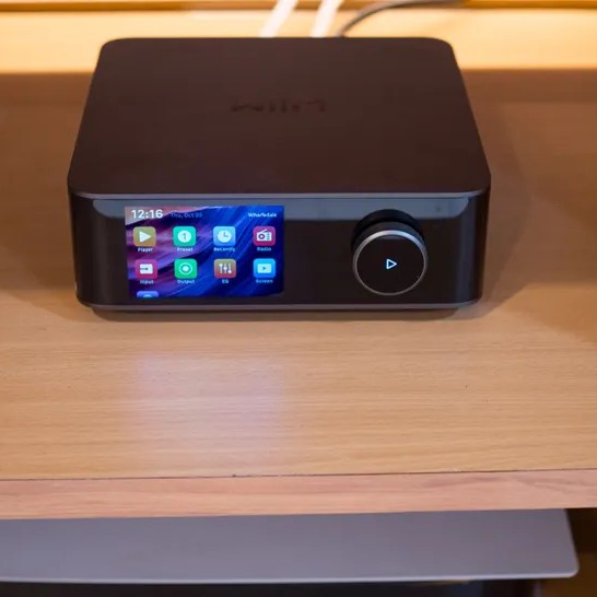 Close-up of the WiiM Amp Ultra streaming amplifier on a desk with speakers